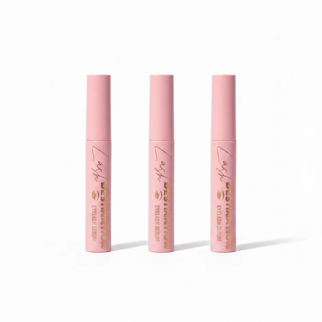 Three LashDestination eyelash serum tubes in soft pink with rose gold lettering standing upright on white background